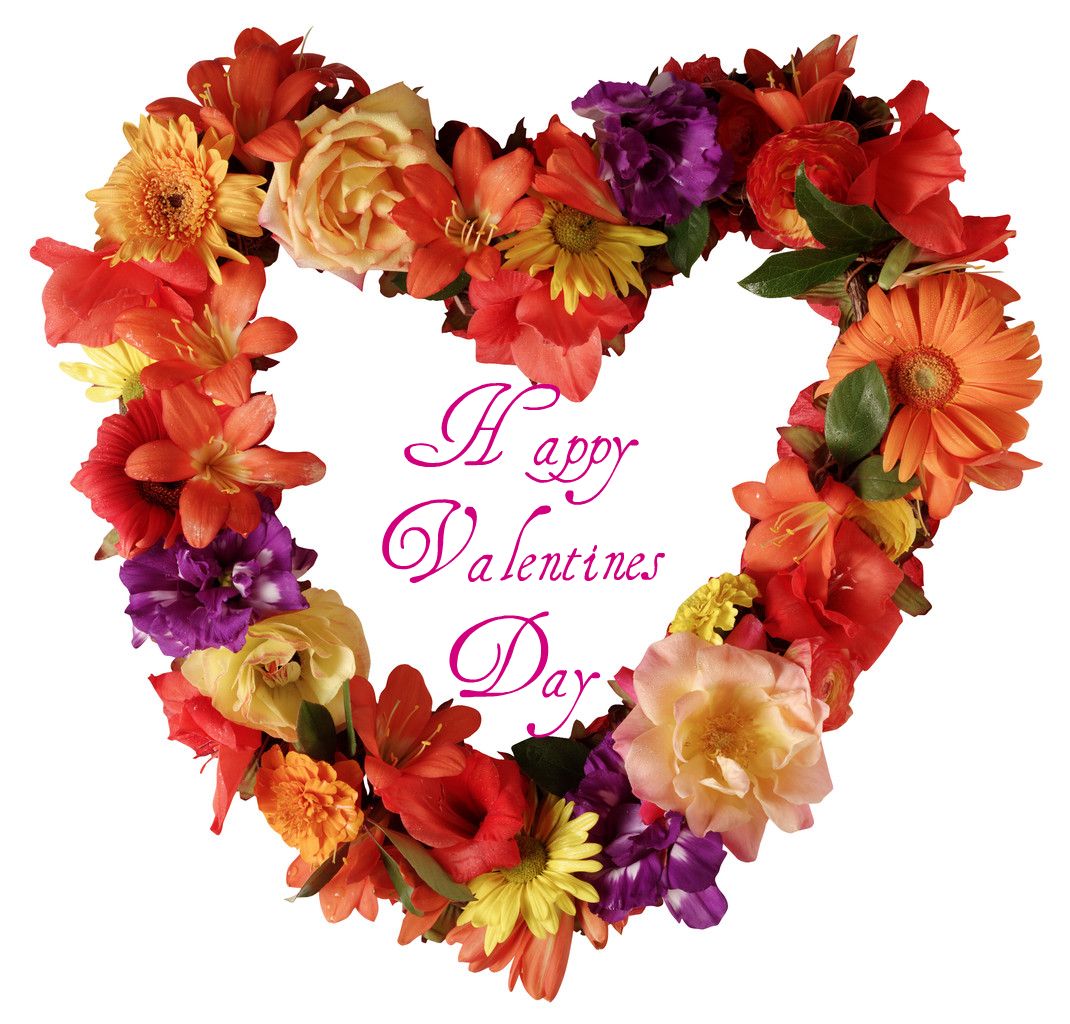 A wreath made out of of flowers in the shape of a heart and in the middle it reads "Happy Valentines Day."