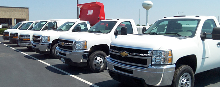 A fleet of white pick up trucks and vans towards the end of the line.