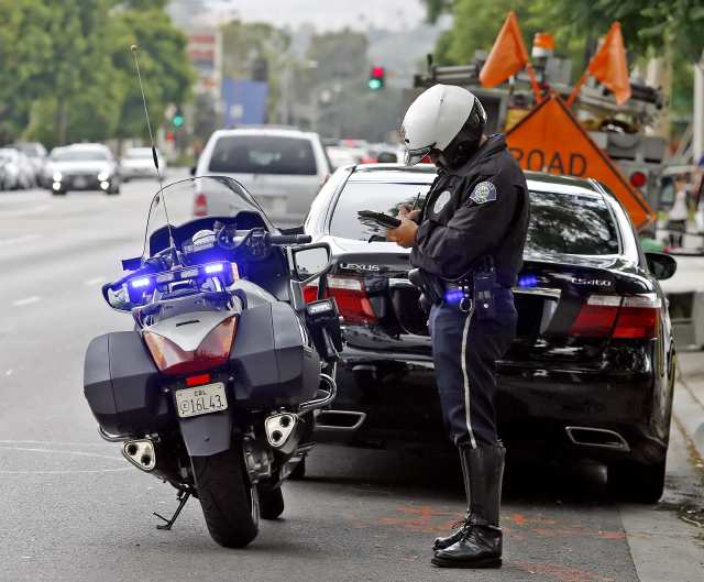 A motorcycle cop writing a ticket.