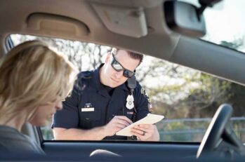 Police officer writing a blonde woman a ticket who is sulking.