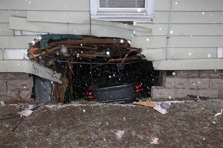 Bizarre car accident where a silver car has crashed through the side of a house and landed in its basement.