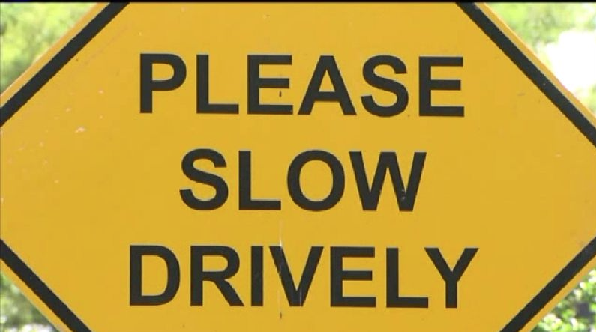 Yellow sign that says "Please Slow Drively."