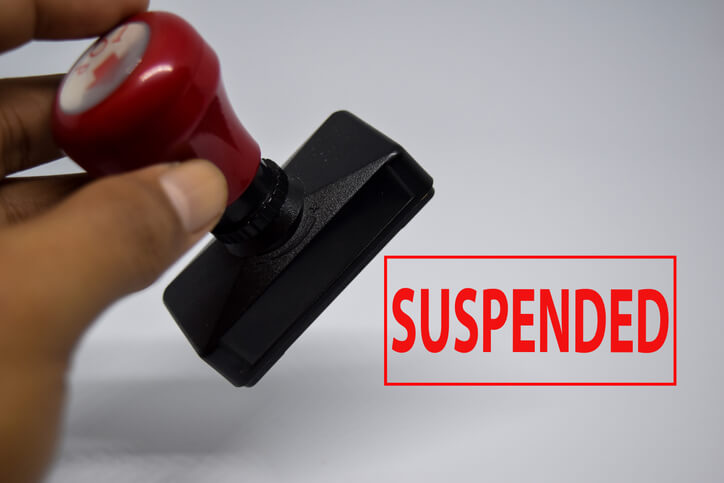 A rubber stamp leaves the word "suspended" on a page in red letters.