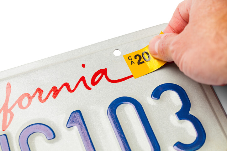 California License Plate with Hand Placing Registration Tab