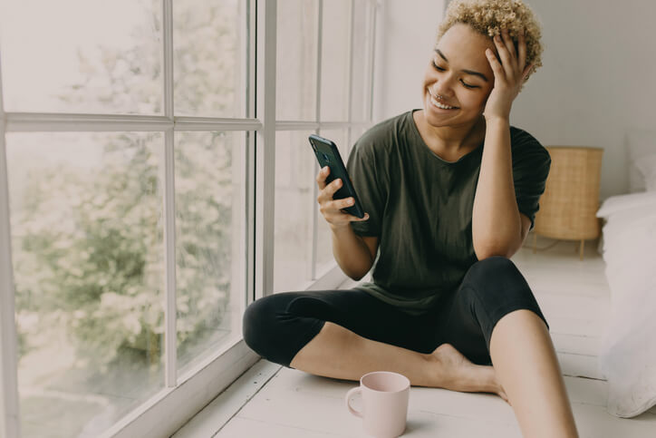 Smiling young woman reads confirmation of her ticket dismissal on her smartphone.