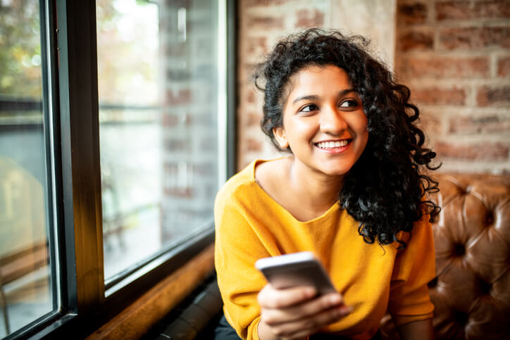 A young woman looks happily at her phone knowing her Georgia traffic ticket issues have been resolved.