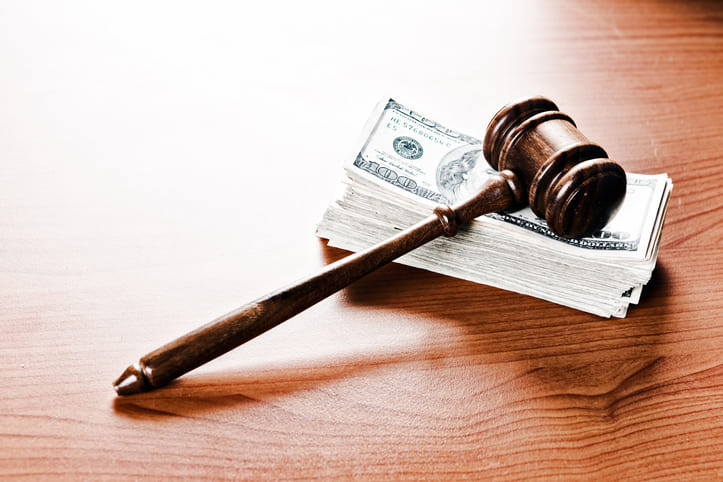 A judge's or auctioneer's gavel acts as a paperweight on a thick stack of banknotes.