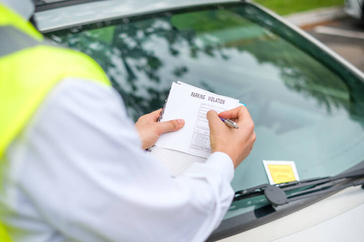 A driver having points added to their license of a parking violation and a ticket is placed on their windshield.