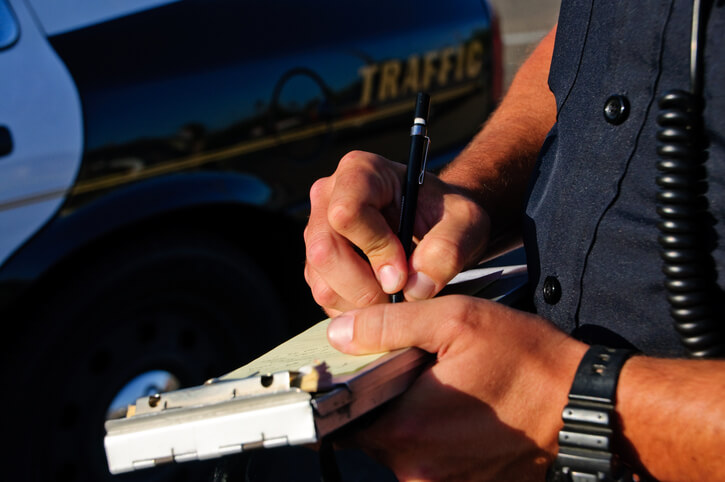 A police officer writing a traffic ticket for a driver who has violated the speed limit