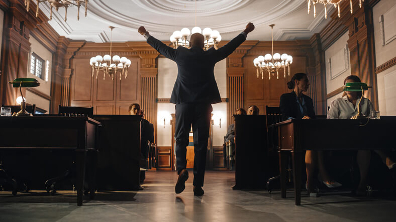 A man walks triumphantly out of a courtroom having successfully contested his traffic ticket thanks to myIMPROV.com's handy guide.