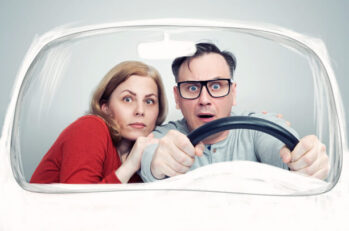 A playful image of a husband and wife driving a vehicle, distressed at the additional insurance premiums they may have to pay thanks to 3 key dangerous driving habits.